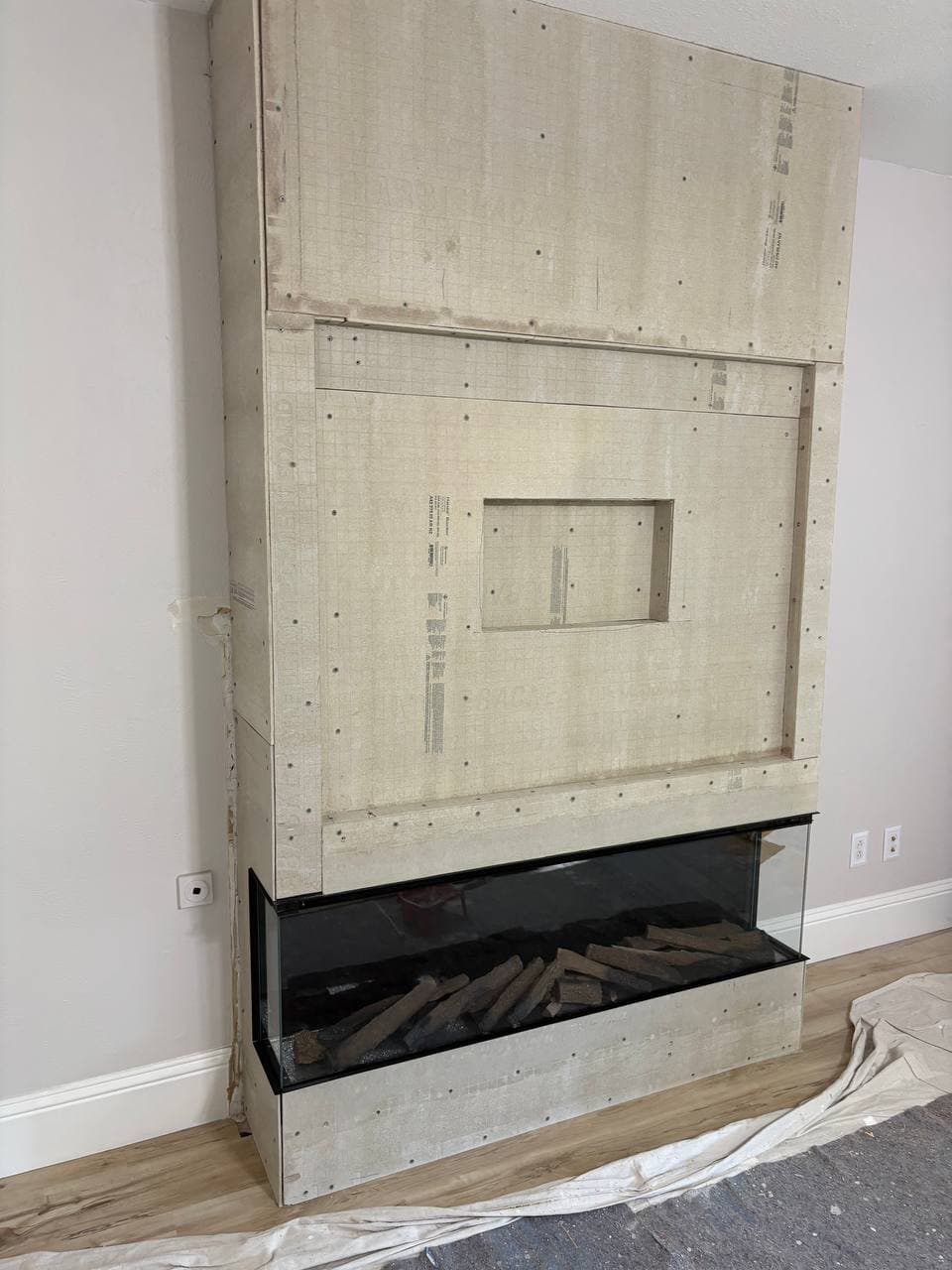 Fireplace surround in progress with cement backer board and electric insert
