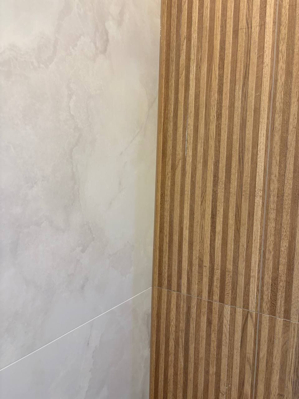 Clean transition between marble tile wall and wood slat panel