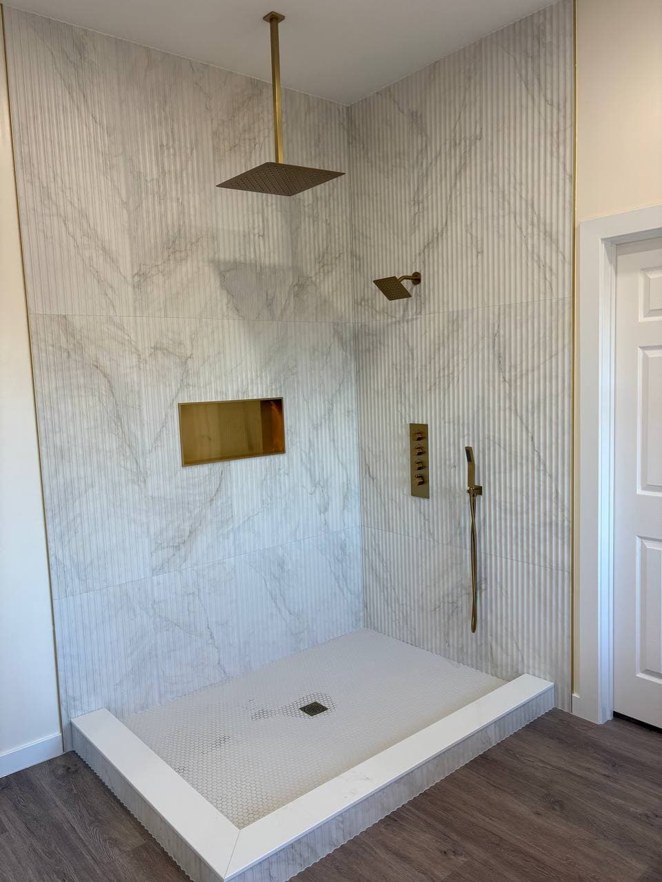 Walk-in shower with marble tile and gold fixtures by Perfect House VL
