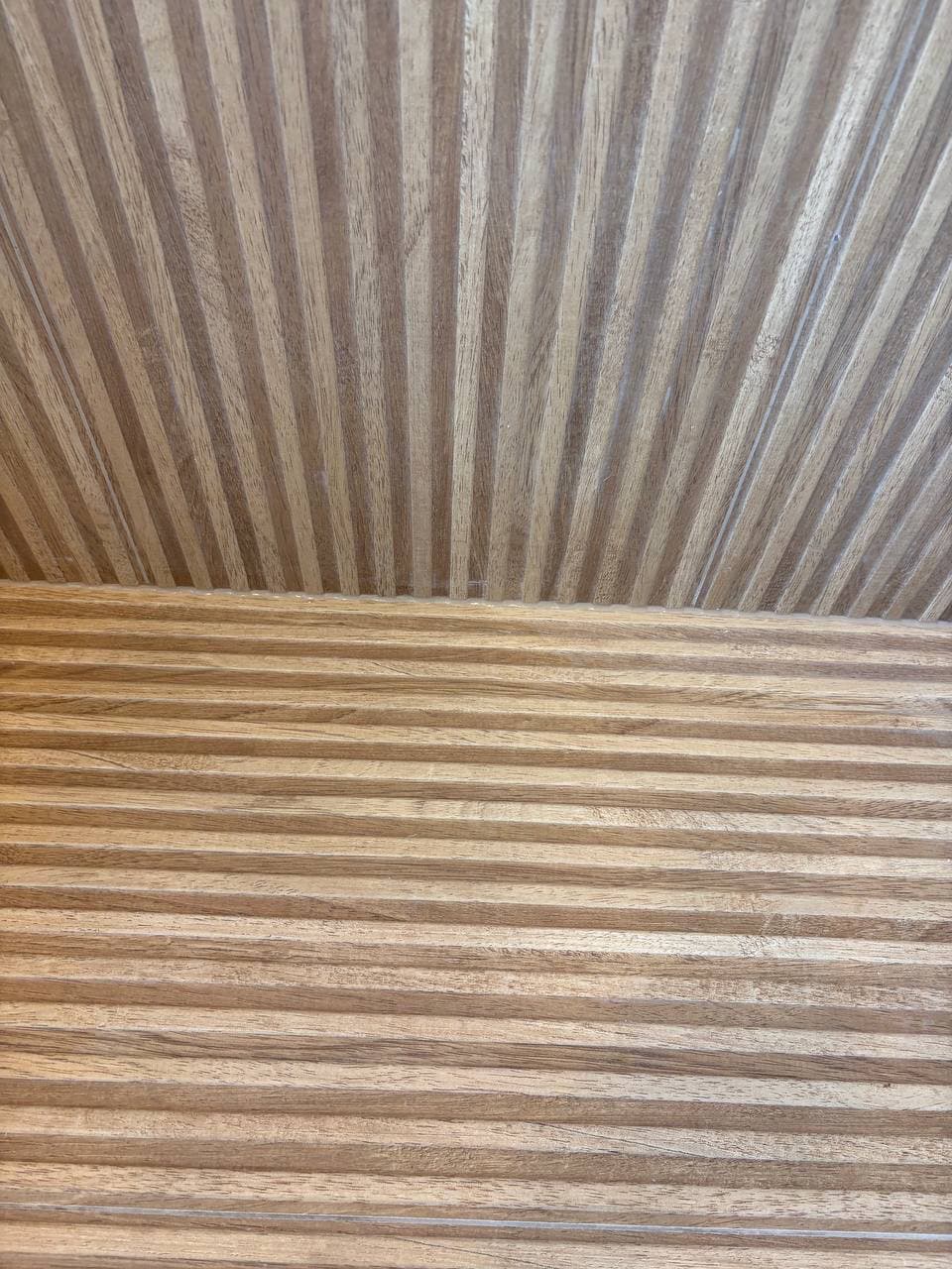 Teak wood slat floor and wall meeting at corner showing seamless craftsmanship